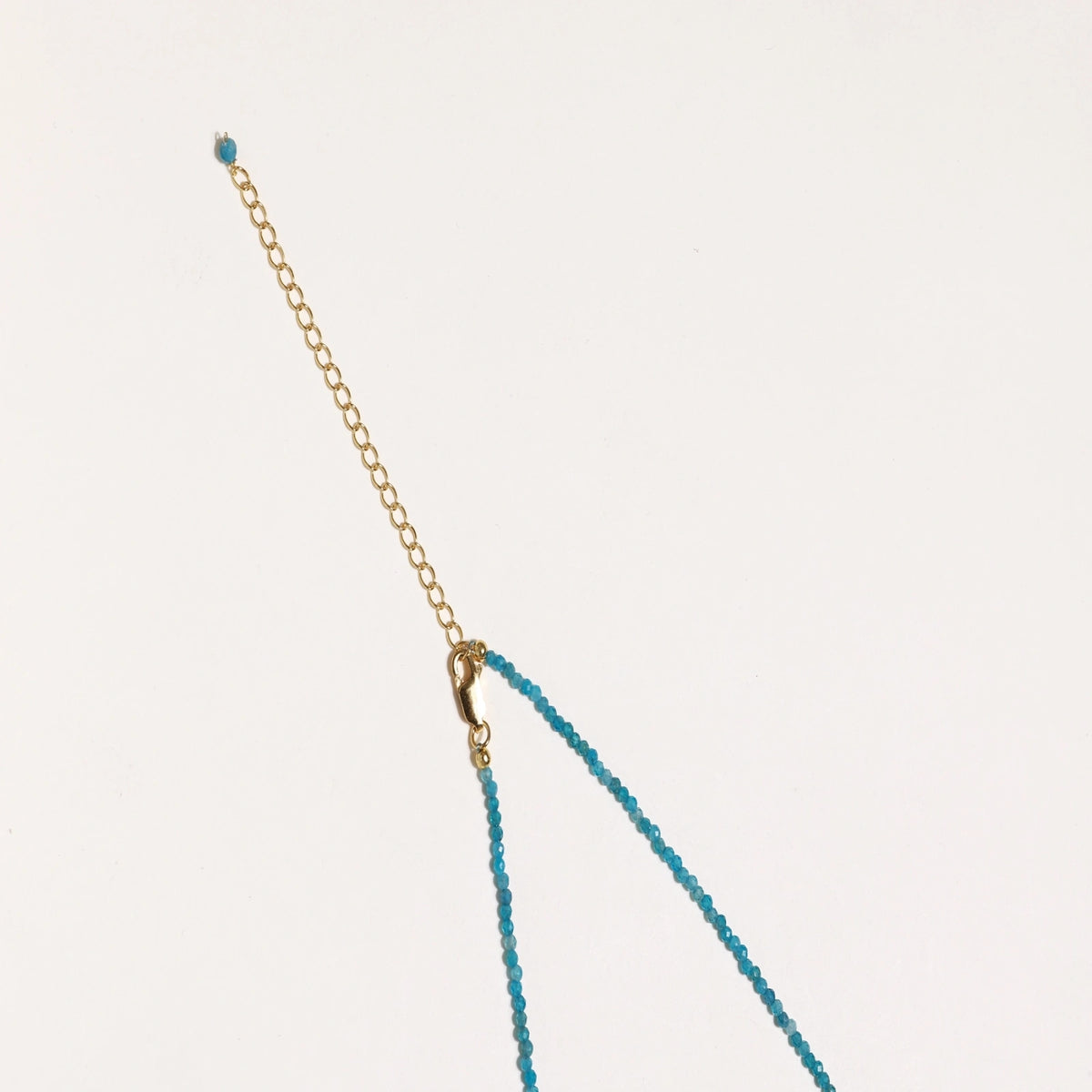 Dainty teal apatite beaded necklace with a single freshwater pearl centerpiece flanked by two small gold beads, adjustable gold clasp.
